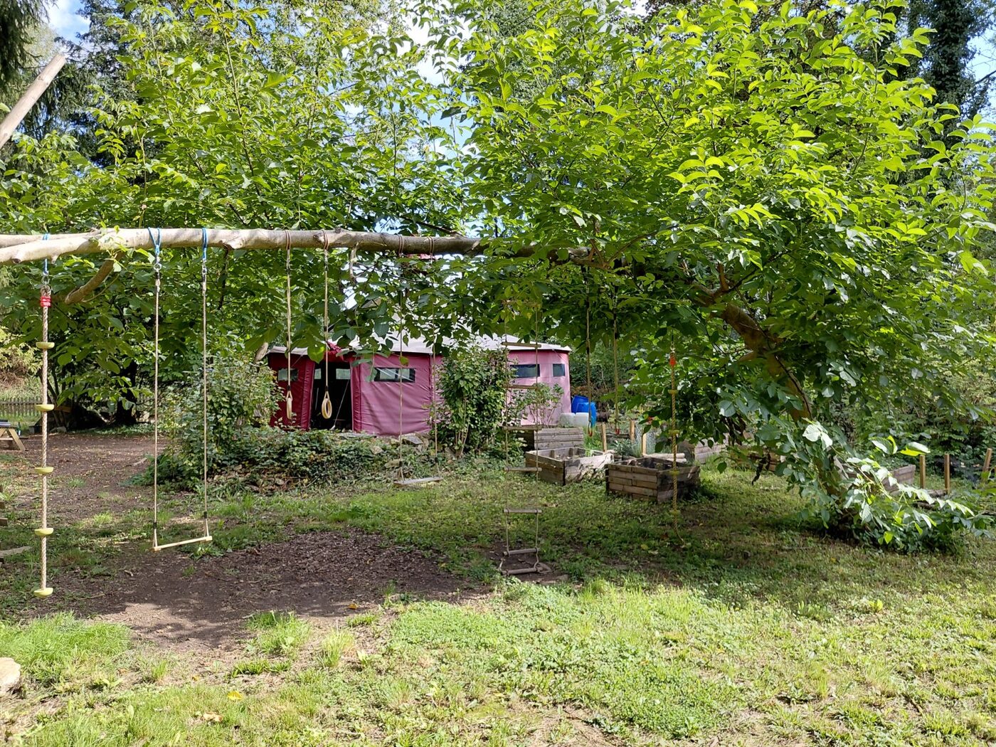 Das Gelände des Waldkindertreffs Völksen mit Kletterelementen und Jurte unter grünen Bäumen